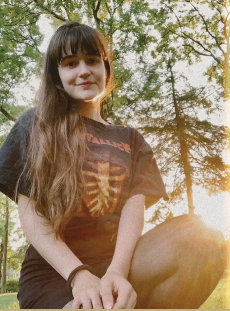 Woman smiling while sitting in a park during sunset.
